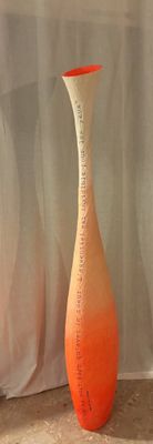 un vase posé par terre devant un rideau