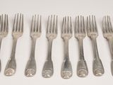 six forks are arranged in a row on a white surface