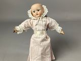 a doll that is wearing a pink dress and a white bonnet