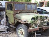 an old green truck that is parked in the dirt