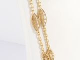 a close up of a gold chain bracelet with leaves on it