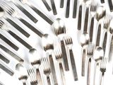 de nombreuses fourchettes et cuillères disposées sur une surface blanche