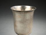 une coupe ancienne en argent posée sur un socle, sur une surface grise