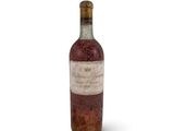 une vieille bouteille de vin posée sur une surface blanche