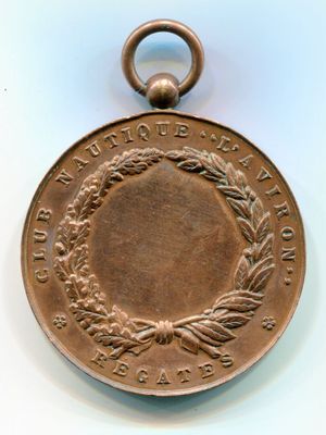 une vieille médaille en bronze ornée d'une couronne, posée sur un fond blanc