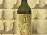 une bouteille de vin posée sur une table devant un mur de tasses