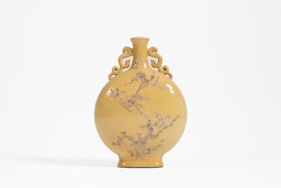 un vase jaune posé sur une surface blanche, sur fond blanc