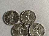 four silver coins sitting on top of each other on a white surface