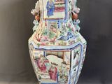 un grand vase avec un tableau posé sur une table