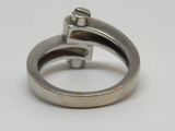 une bague en argent ornée d'une croix, posée sur un fond blanc