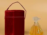 a small bottle of perfume next to a red box