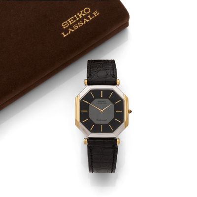 a close up of a black and gold wrist watch next to a book
