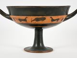an old black and orange vase with animals on it on a white surface