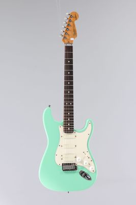 une guitare électrique suspendue à une corde sur un fond gris