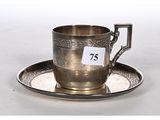 une tasse et une soucoupe en argent posées sur une soucoupe portant le numéro 75