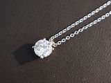a close up of a diamond pendant on a chain on a table