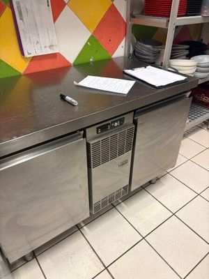 un plan de travail en acier inoxydable dans une cuisine dont les murs sont recouverts de carreaux colorés