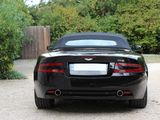 a black sports car parked in a driveway with trees in the background