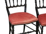 pair of black painted chairs with red upholstered cushions