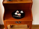 a small wooden table with a plate of cupcakes on it