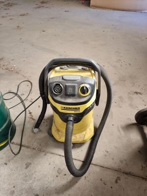un aspirateur jaune et noir posé par terre à côté d'une poubelle verte