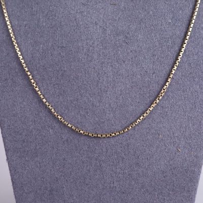 une chaîne en or avec un maillon orné de perles, posée sur un mannequin