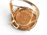 a gold ring with a coin in it on a white surface