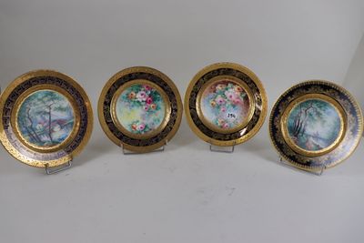 four plates with floral designs on them sitting on a white surface