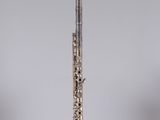 a silver flute on a clear stand against a gray background
