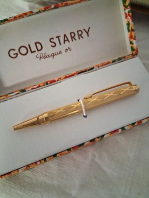 un stylo en or posé dans une boîte sur un lit