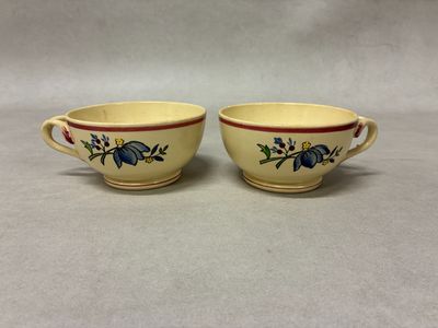 two yellow cups with blue flowers on them sitting on a table