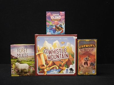 trois jeux de société empilés les uns sur les autres sur une table