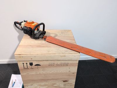 an orange chainsaw sitting on top of a wooden box next to a box