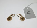 a pair of gold earrings with a price tag on a white table