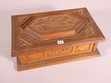 wooden box with carved design on top of it on a white surface