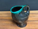 a black and green vase sitting on a wooden table