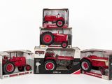 three red toy tractors are stacked on top of each other