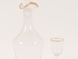 a clear glass decanter with a gold rim and a glass goblet