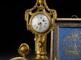 une horloge en or posée à côté d'une photo représentant un homme et une femme