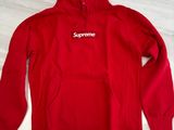 a red supreme hoodie sitting on top of a marble table