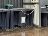 many black trash bins lined up in front of a building