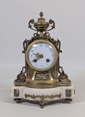 une horloge en or posée sur un socle en marbre