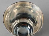 a small silver bowl with a handle on a table