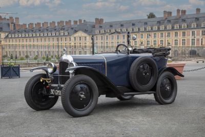 une voiture de collection garée sur un parking devant un grand immeuble