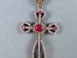 a close up of a diamond cross pendant on a white surface