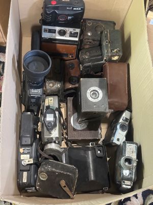 une boîte en carton remplie de vieux appareils photo et d'autres objets