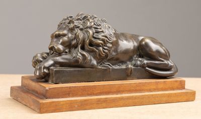 bronze statue of a lion resting on a block on a table