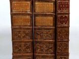 three old books are stacked on top of each other on a white surface