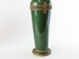 un vase vert posé sur une table, sur fond blanc