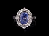 an oval blue sapphire and diamond ring on a black background